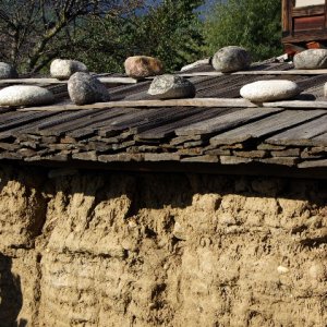 Bhutan - traditional house with earth walls and stones used to secure the roof against strong winds